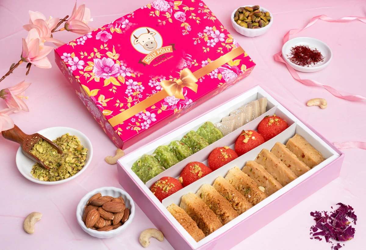 Open mixed sweets box beside the floral Rolly Polly Cow packaging